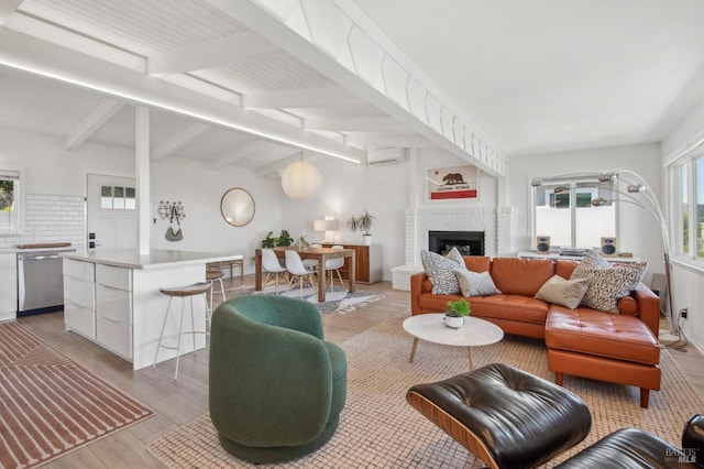 living area with lofted ceiling with beams, light wood-type flooring, a brick fireplace, and a wall mounted AC