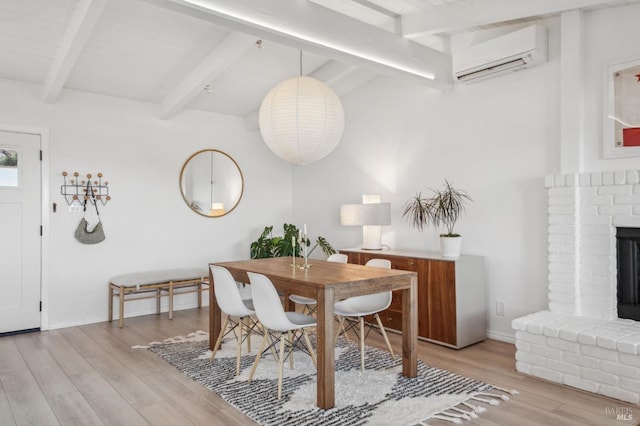 dining room featuring a wall mounted air conditioner, baseboards, lofted ceiling with beams, and light wood finished floors