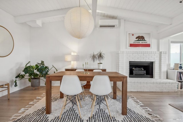 dining room featuring baseboards, a wall mounted air conditioner, lofted ceiling with beams, a fireplace, and wood finished floors