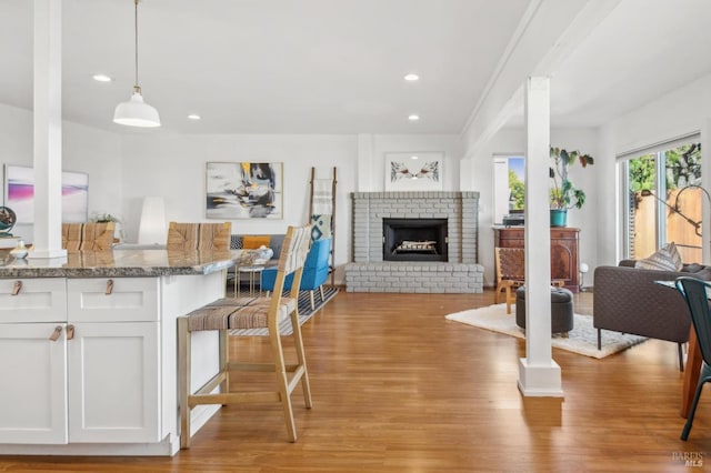 living room featuring a brick fireplace, recessed lighting, and light wood-type flooring