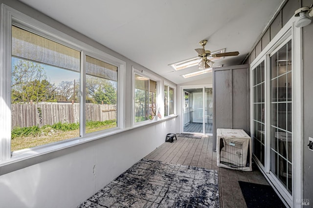 unfurnished sunroom with a ceiling fan, a healthy amount of sunlight, and a skylight