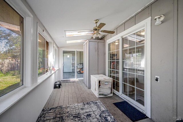 sunroom / solarium with wood-type flooring, ceiling fan, and vaulted ceiling with skylight