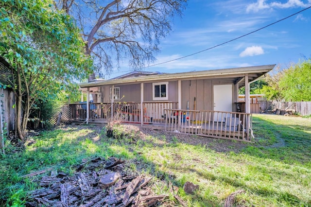 back of property with a lawn, a fenced backyard, a wooden deck, and a chimney