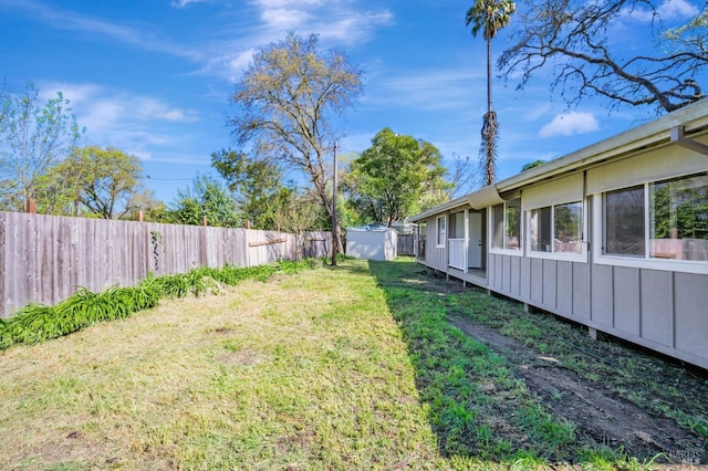 view of yard featuring an outdoor structure, a fenced backyard, and a storage shed
