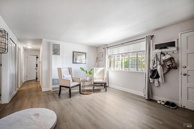 living area featuring baseboards, wood finished floors, and a heating unit