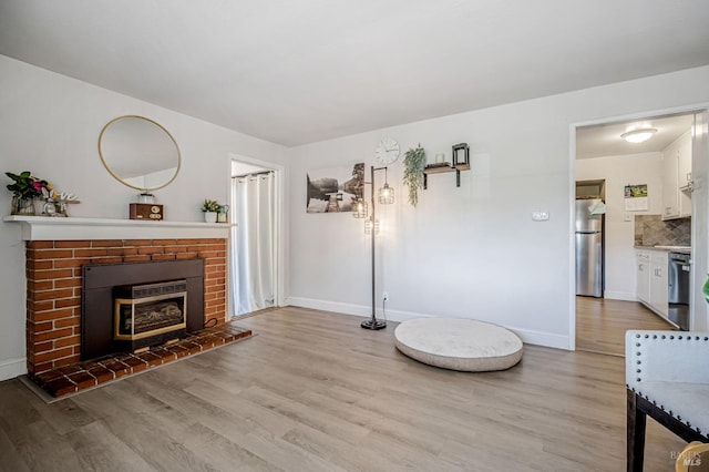 living room with baseboards, light wood-style flooring, and a fireplace