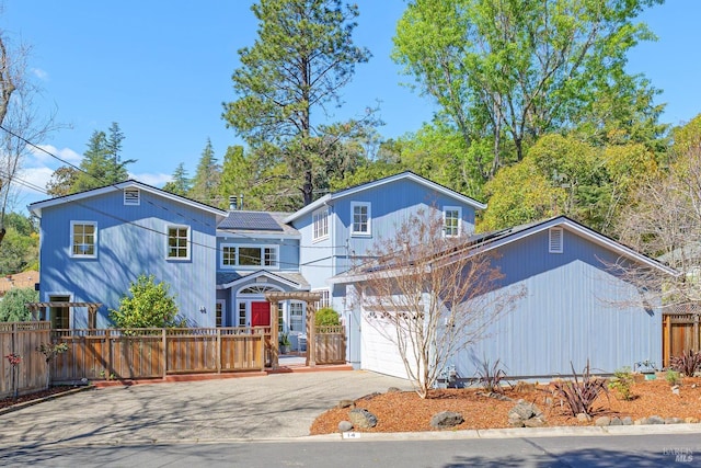 view of front of house with solar panels, concrete driveway, and fence