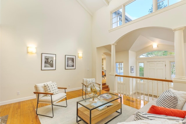 living area with decorative columns, light wood-style floors, and arched walkways