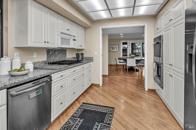 kitchen with baseboards, light stone countertops, light wood-style flooring, white cabinets, and stainless steel appliances