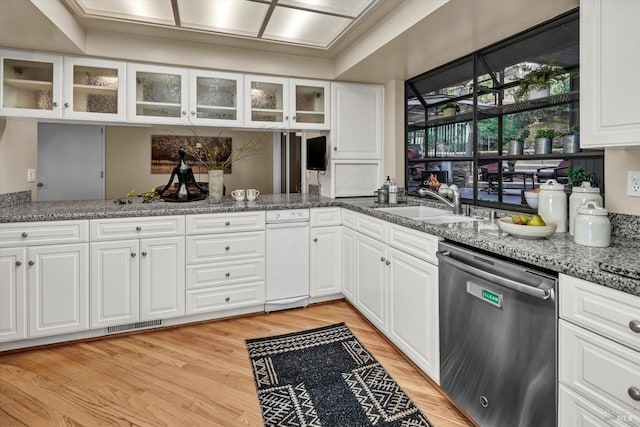 kitchen featuring stone counters, a sink, glass insert cabinets, dishwasher, and light wood-type flooring