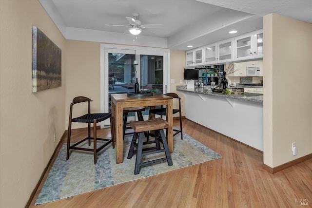 dining space featuring baseboards, light wood-style floors, and ceiling fan