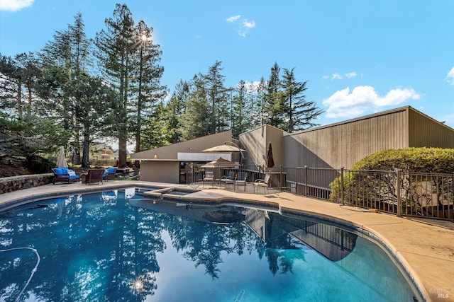 view of pool featuring a patio, fence, and a pool with connected hot tub