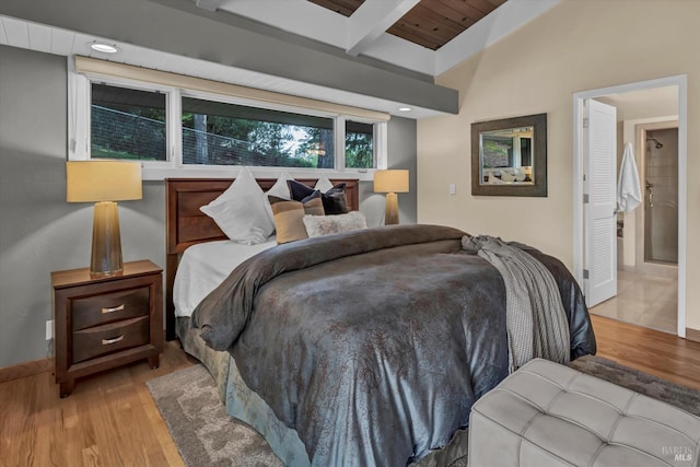bedroom with beamed ceiling, wood finished floors, and baseboards