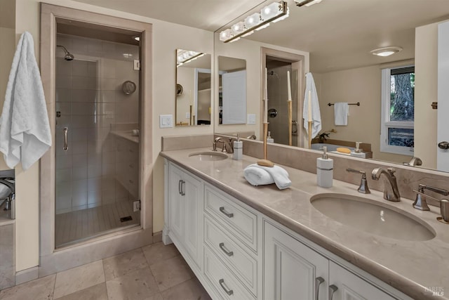 full bathroom featuring double vanity, a stall shower, tile patterned floors, and a sink