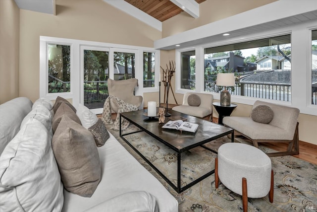 living area with a wealth of natural light, wooden ceiling, lofted ceiling with beams, and wood finished floors