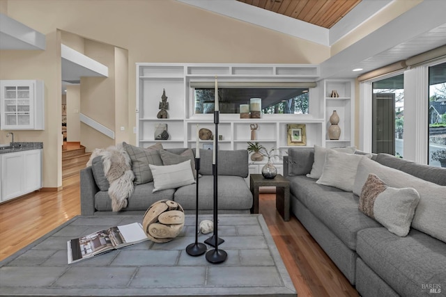 living area featuring vaulted ceiling, stairway, built in features, and wood finished floors