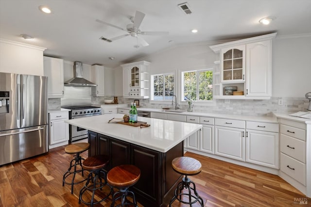 248 Vine St, Vacaville, CA 95688 - kitchen with stainless steel appliances, wall chimney range hood, a kitchen bar, ornamental molding, and glass insert cabinets