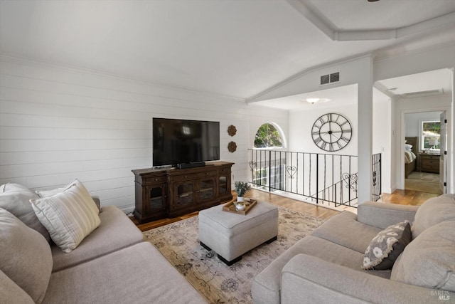living room with visible vents, wood finished floors, wood walls, and vaulted ceiling