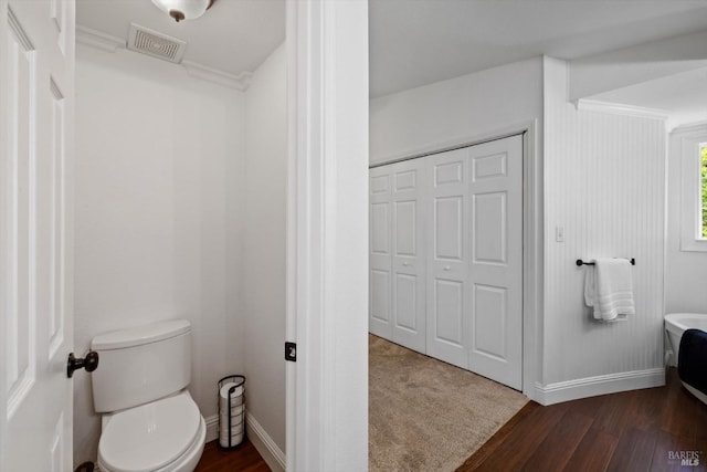 bathroom with crown molding, visible vents, baseboards, toilet, and wood finished floors