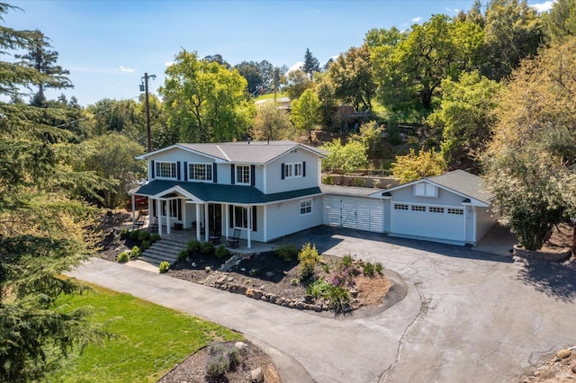 view of front of property with a garage, a porch, an outdoor structure, and curved driveway