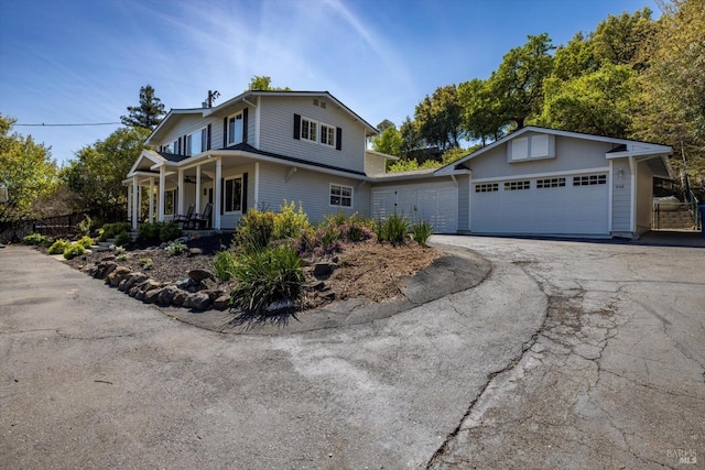 traditional-style house featuring a porch, fence, a garage, and aphalt driveway