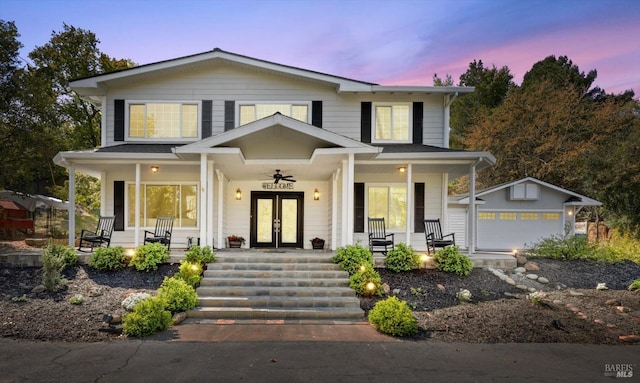 view of front of home with an outdoor structure, covered porch, a detached garage, and french doors