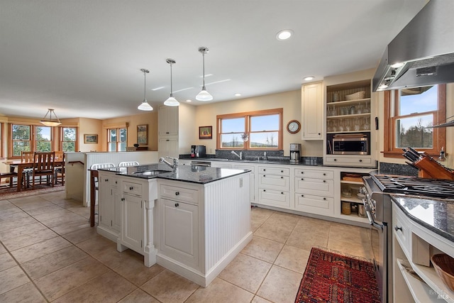 kitchen featuring wall chimney range hood, open shelves, appliances with stainless steel finishes, a sink, and plenty of natural light