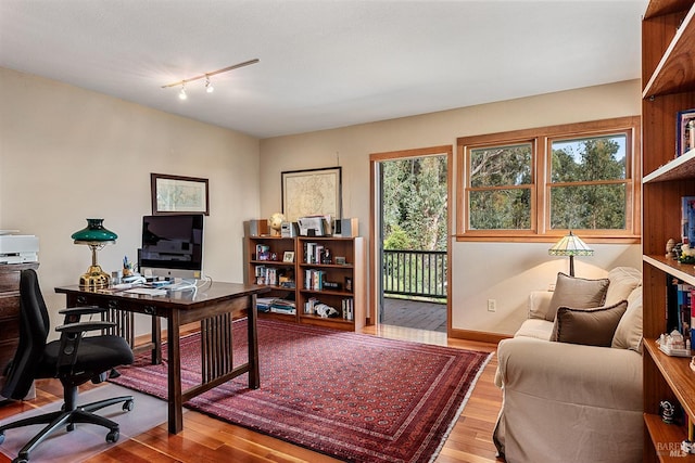 office with track lighting, plenty of natural light, and wood finished floors