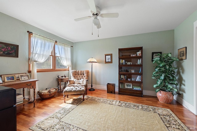 sitting room with baseboards, ceiling fan, and wood finished floors
