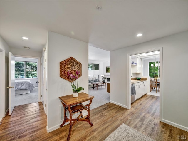 corridor with recessed lighting, plenty of natural light, and light wood-style floors