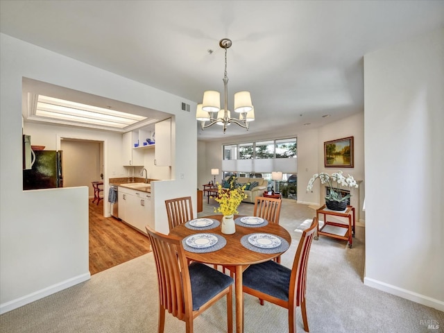 dining space with a chandelier, light carpet, and baseboards