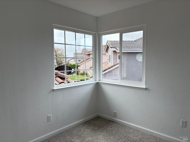 carpeted empty room with a textured wall and baseboards