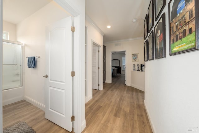 corridor featuring baseboards, visible vents, recessed lighting, crown molding, and light wood-type flooring