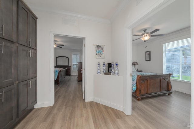 hall with visible vents, light wood-style flooring, crown molding, and baseboards