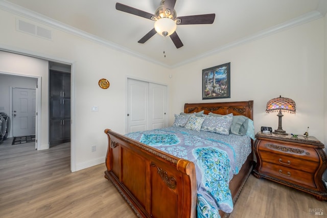 bedroom with visible vents, crown molding, baseboards, light wood-type flooring, and a closet