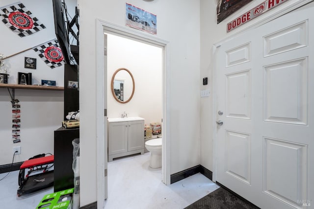 bathroom with vanity, toilet, baseboards, and concrete floors