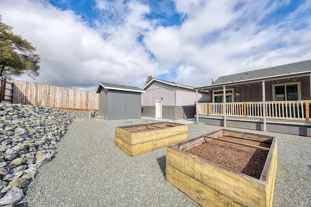 view of yard with a storage shed, a vegetable garden, fence, and an outbuilding
