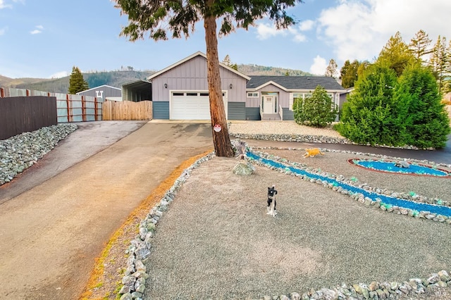 ranch-style house with fence, concrete driveway, a carport, a garage, and board and batten siding