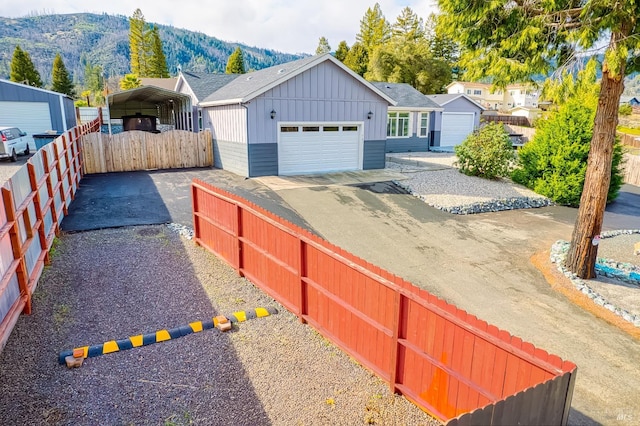 view of front of home featuring a detached garage, fence, a mountain view, board and batten siding, and a detached carport