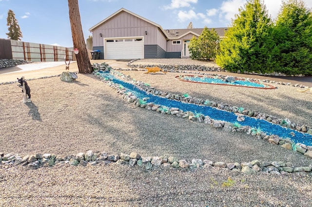 ranch-style home featuring a garage, board and batten siding, driveway, and fence