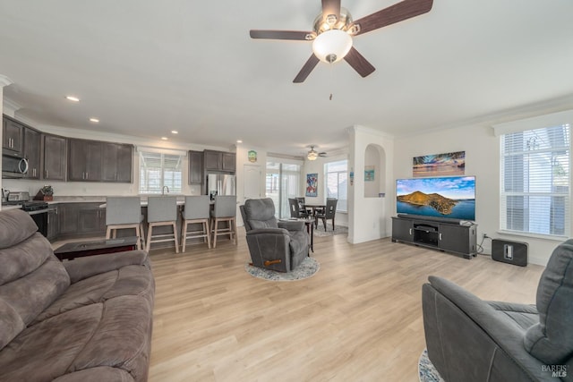 living area with crown molding, light wood-style flooring, recessed lighting, and a ceiling fan