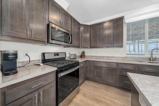 kitchen featuring dark brown cabinets, stainless steel appliances, light countertops, and a sink