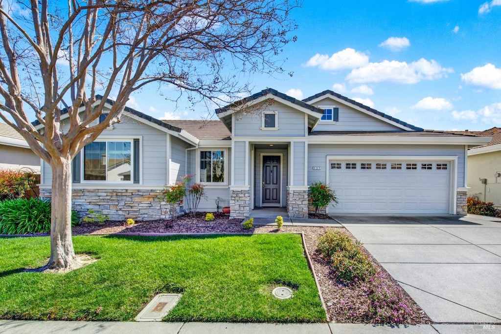 view of front of property featuring a garage, stone siding, concrete driveway, and a front yard