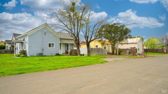 view of front of home with a front yard, central air condition unit, and fence
