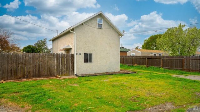 exterior space featuring stucco siding, a lawn, and a fenced backyard