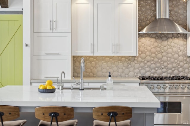 35 Bernard St, Mill Valley, CA 94941 - kitchen with high end stove, wall chimney exhaust hood, a breakfast bar area, decorative backsplash, and white cabinets