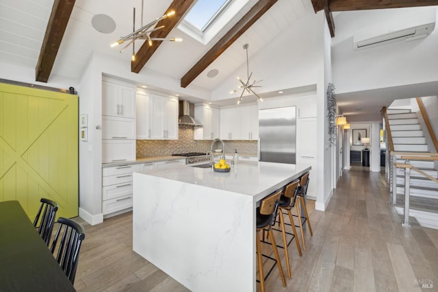 35 Bernard St, Mill Valley, CA 94941 - kitchen featuring wall chimney range hood, stainless steel built in refrigerator, light wood-style flooring, and a kitchen bar