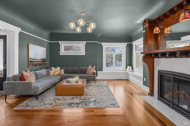 living area featuring a fireplace, wood finished floors, and a notable chandelier
