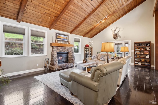 living room featuring a stone fireplace, baseboards, dark wood finished floors, and a healthy amount of sunlight