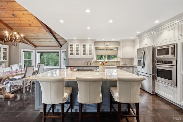 kitchen featuring a spacious island, stainless steel appliances, backsplash, and a notable chandelier